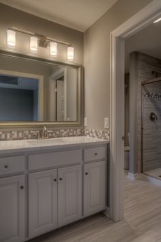 a large bathroom with white cabinets and marble counter tops