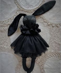 a black bunny doll is sitting on a lace doily