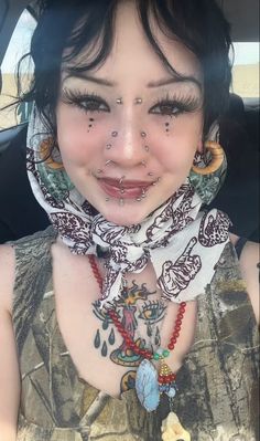 a woman with tattoos on her face and neck in the back seat of a car