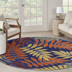 a blue rug with orange and yellow leaves on it in front of a white couch