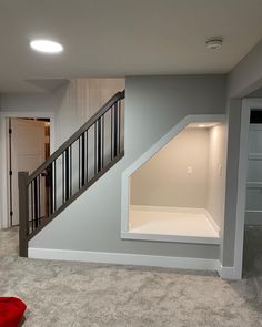 an empty living room with stairs leading up to the second floor and storage space below