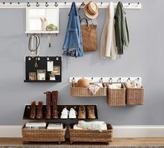 an organized entryway with baskets, boots and coats hanging on the wall next to it