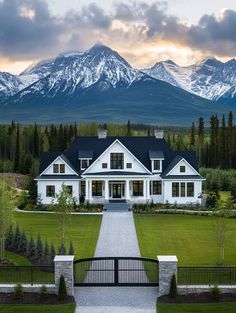 a large white house with mountains in the backgroung and trees on either side