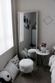 a bedroom with a mirror, stool and table in it