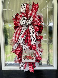 a red and white bow with dog paw prints on it is hanging in front of a window