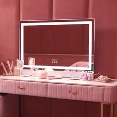 a pink vanity with a mirror and various items on the top shelf in front of it