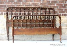 an old wooden bed frame against a brick wall