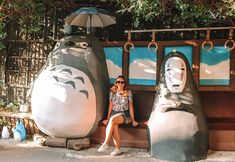 a woman sitting next to two large statues