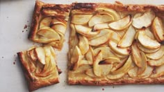 an apple tart is cut into slices on a cutting board next to a knife