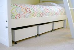 a white bed with drawers underneath it in a small room next to a wall and carpeted floor