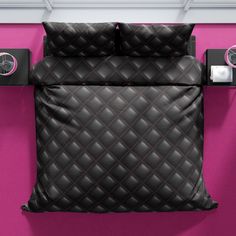 a black quilted comforter and pillow on a pink wall with two alarm clocks