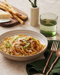 a white bowl filled with pasta on top of a table next to utensils