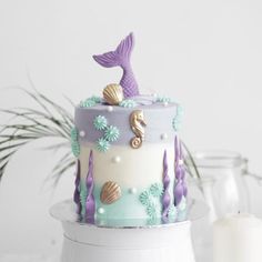 the cake is decorated with mermaids and seashells on it's sides