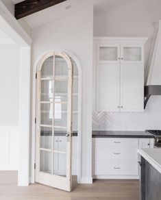 a kitchen with white cabinets and an arched glass door