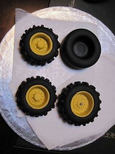 four black and yellow wheels on top of a white cake with silver foil around it