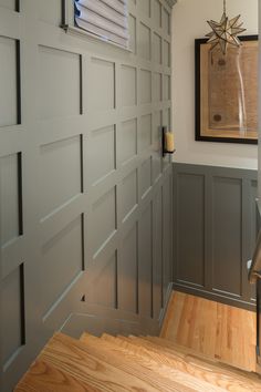 a wooden stair case in a house with gray walls and wood steps leading up to the front door