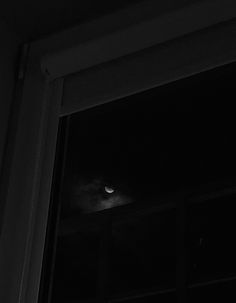 a black and white photo of a cat looking out the window at the moon in the sky