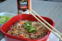 a red bowl filled with food and chopsticks on top of a white plate