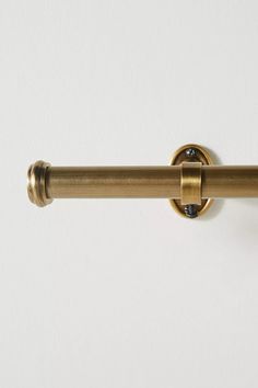 a close up of a metal curtain rod on a white wall with a black dot in the center