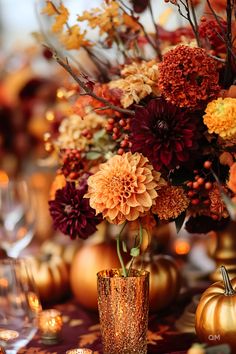 a vase filled with lots of flowers next to candles and pumpkins on a table