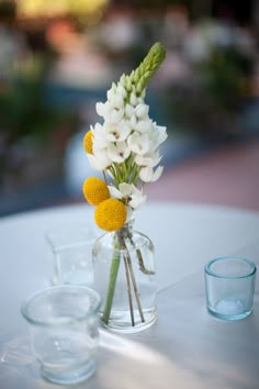 a vase filled with flowers sitting on top of a table next to a glass cup