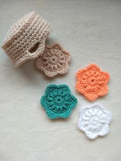 four crocheted flowers sitting next to each other on a white tablecloth,