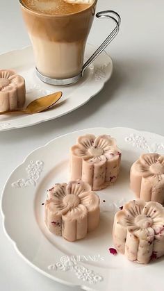 some desserts are sitting on a white plate next to a cup of coffee