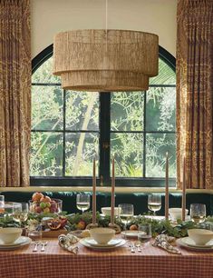 a dining room table with plates and bowls on it in front of a large window