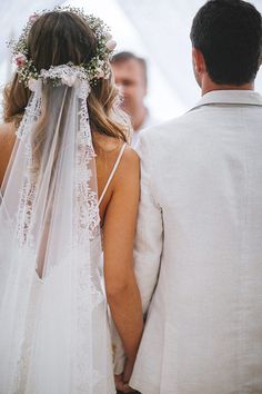 a bride and groom looking at each other in front of a white tent with their back to the camera