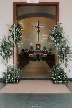 the entrance to a church decorated with greenery and white flowers is seen through an open door