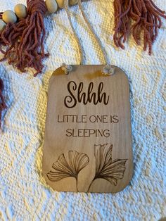 a wooden sign that says, she is little one is sleeping with tassels around it