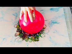 a person's hand on top of a red object in the middle of a table