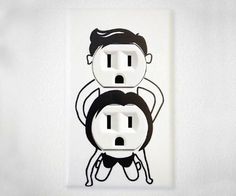 an electrical outlet with two black and white cartoon characters on it, one holding the other's head