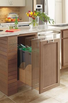 a kitchen with wooden cabinets and stainless steel appliances, including an island that has trash cans in it