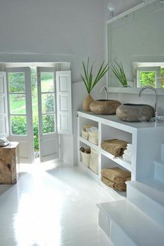 a white bathroom with two sinks and open doors