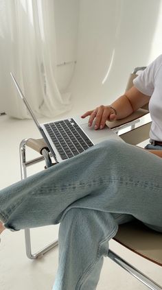 a woman sitting in a chair using a laptop computer