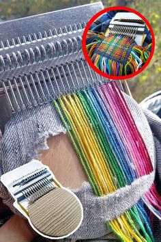 a close up of a person's hand holding a comb with many different colored yarns on it