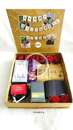 an open box with many items in it on a white tablecloth and some red roses