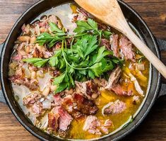 a pan filled with meat and vegetables next to chopsticks on a wooden table