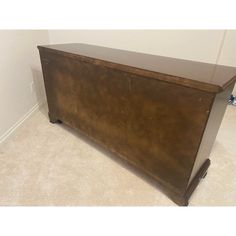 a large wooden chest sitting on top of a carpeted floor next to a wall