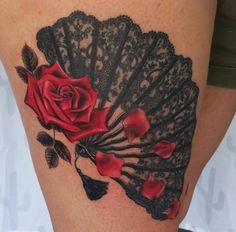 a woman's thigh with roses and an old fan tattoo on her leg,