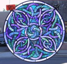 a circular stained glass window on the side of a building with cars parked in front of it