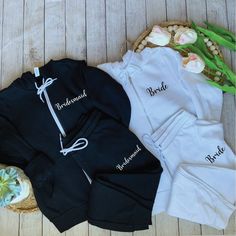 three personalized baby clothing laid out on a wooden floor next to flowers and an empty basket