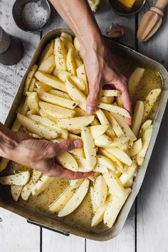 two hands reaching for potatoes in a pan