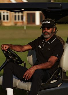 a man sitting in the driver's seat of a golf cart with his hand on the steering wheel