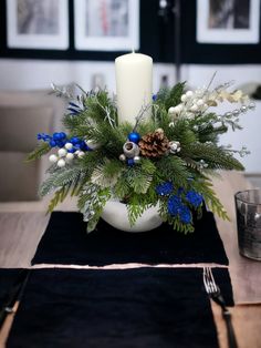 a white candle is sitting on top of a table with blue and white flowers in it