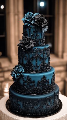 a three tiered blue wedding cake with flowers on the top and sides, sitting on a table in front of columns