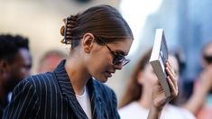 a woman is reading a book while standing in front of a group of other people