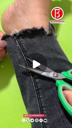 someone using scissors to cut the back of their jeans with green handles and black feet