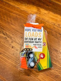 a birthday card in a plastic bag on top of a wooden table next to a toy car